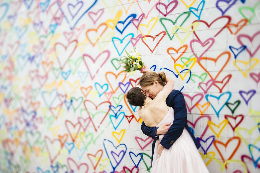Two women hugging near a painted wall 