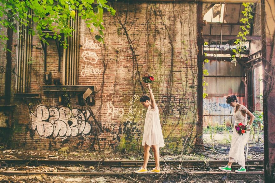 Two woman in wedding dresses walking in an abandoned railway station 