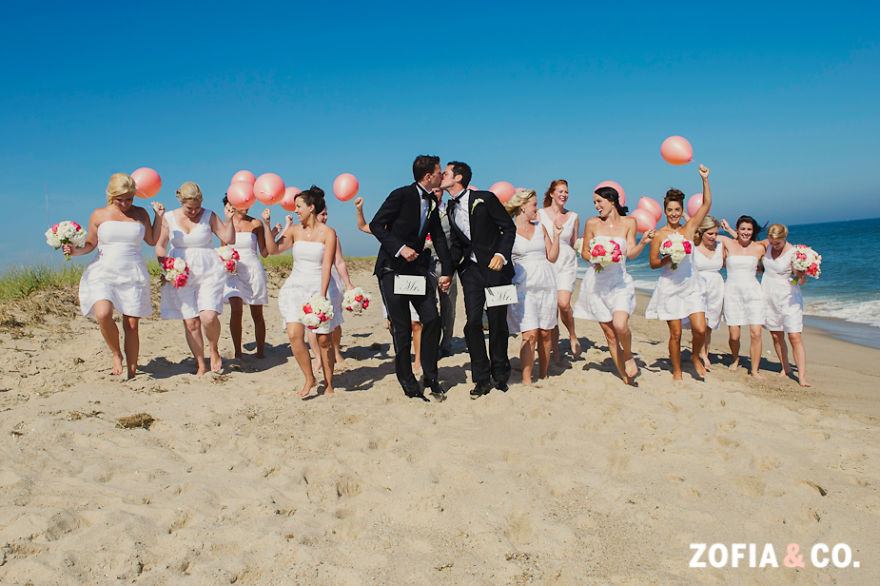 Two men kissing with multiple women behind them 