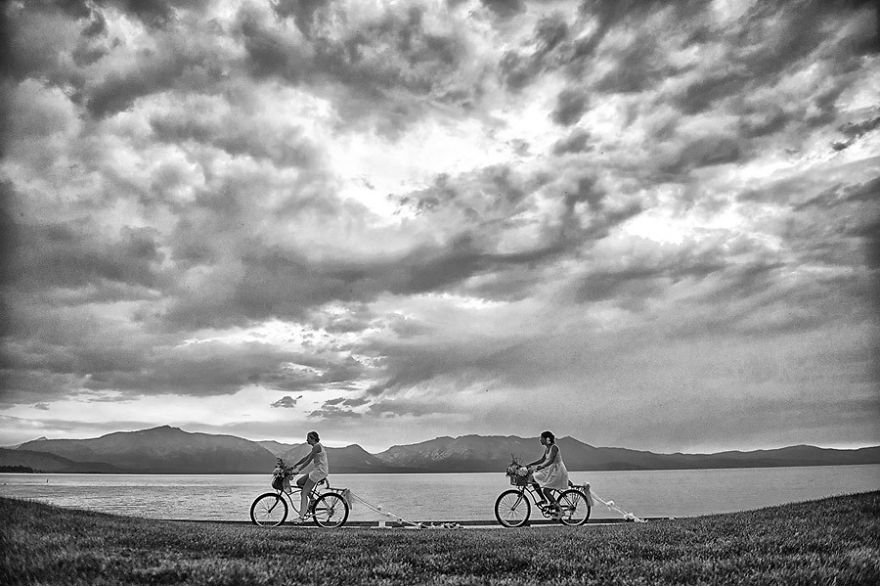 Two women riding bikes near a lake 