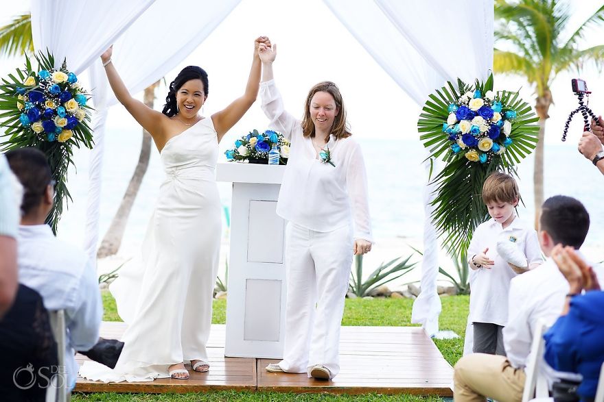 Two women holding hands and looking at other people 