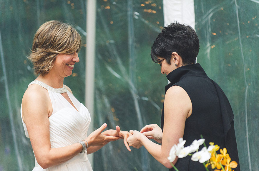 One woman putting a ring on other woman finger 