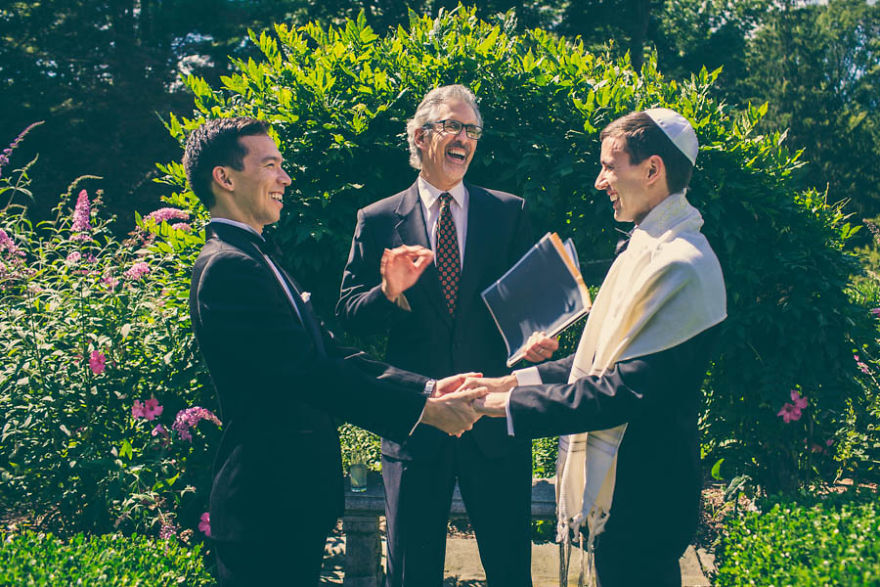 Two men holding hands near a pastor 