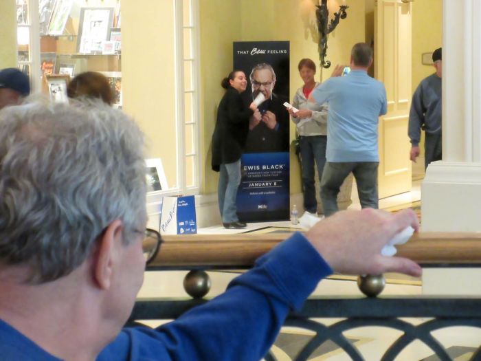 Lewis Black Looking On While Fans Pose With A Lewis Black Poster