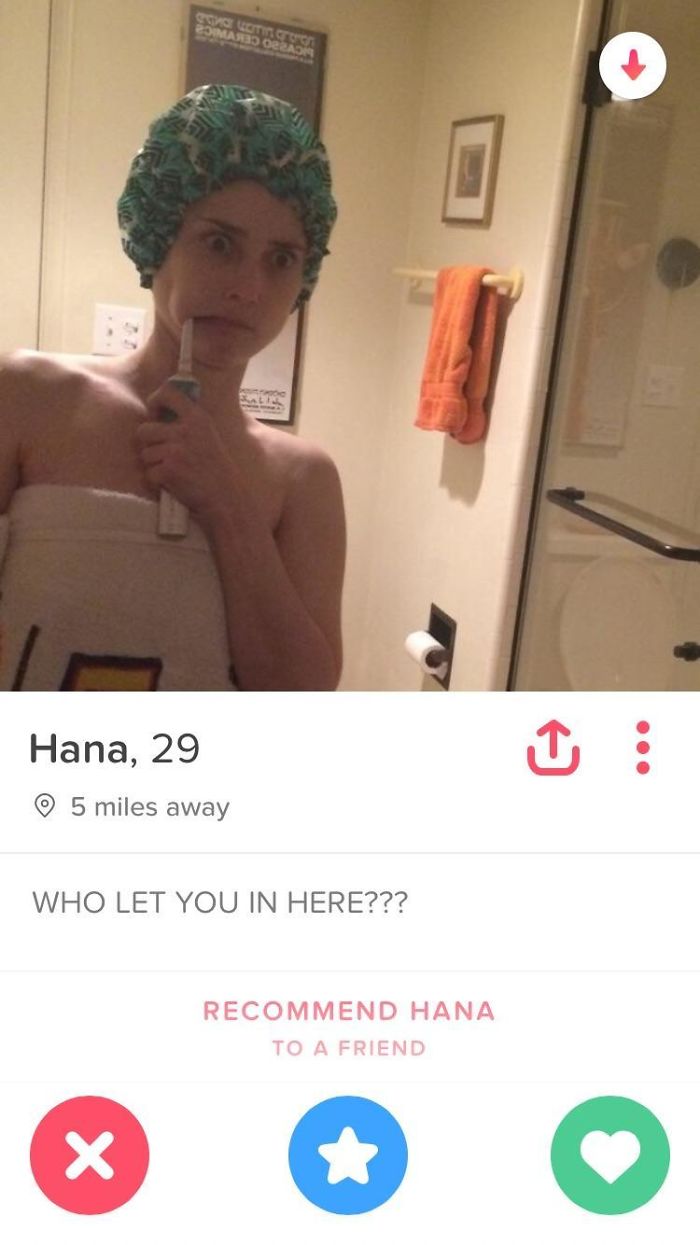 Funny Tinder profile of Hana, 29, surprised in a bathroom with a toothbrush and shower cap.