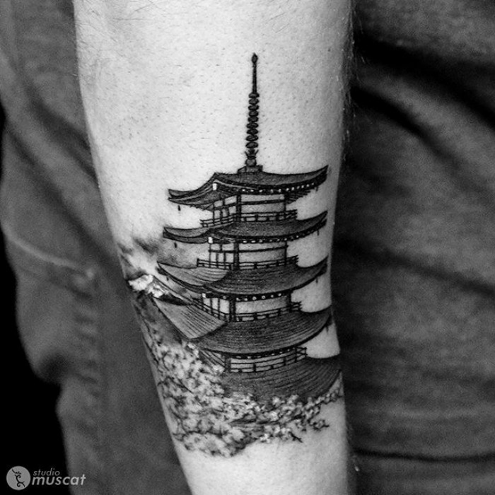 Tattoo of a pagoda temple on an arm, featuring detailed architectural elements in black and gray ink.