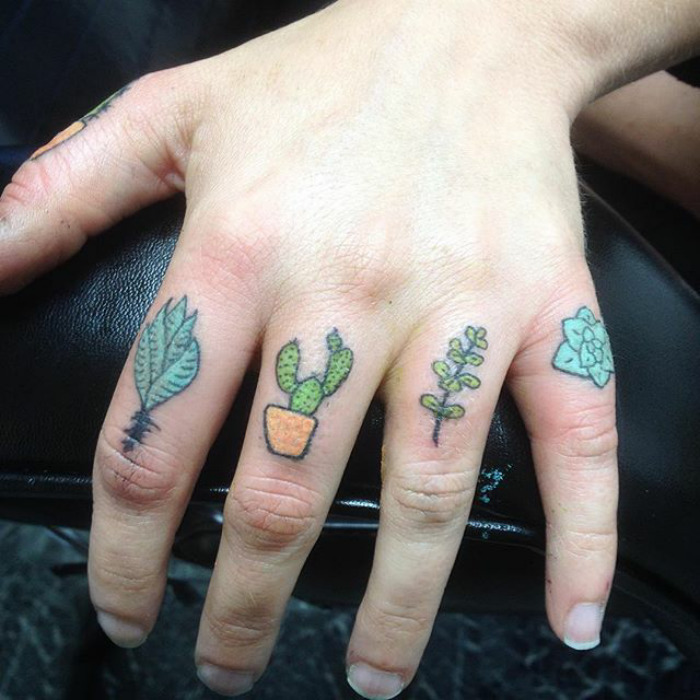 Close-up of succulent tattoos on fingers, featuring cactus and leafy designs.
