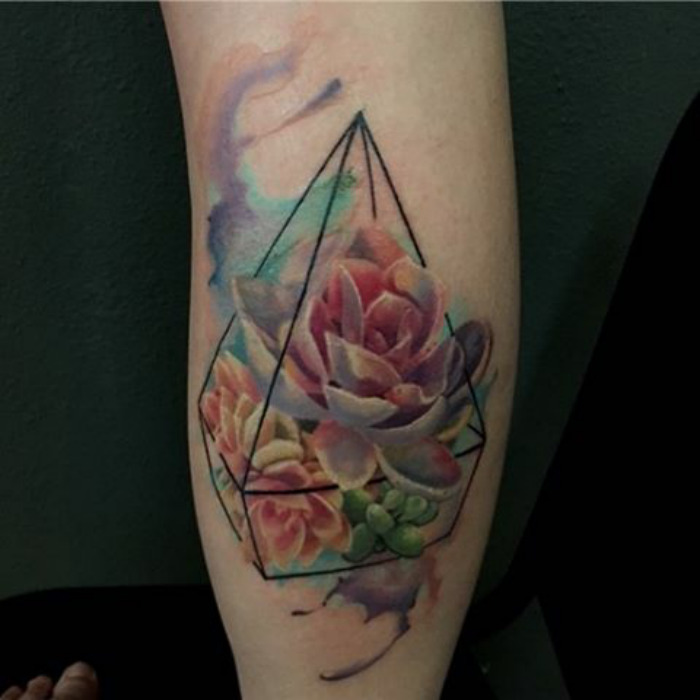 Succulent tattoo design with vibrant colors and geometric shapes on an arm.