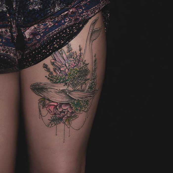 Succulent tattoo design featuring a whale and vibrant plants on a person's thigh.