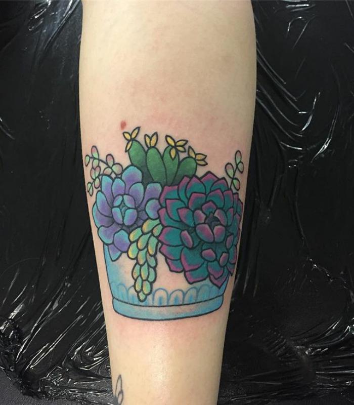 Colorful succulent tattoo design on arm featuring vibrant plant arrangement in a pot.