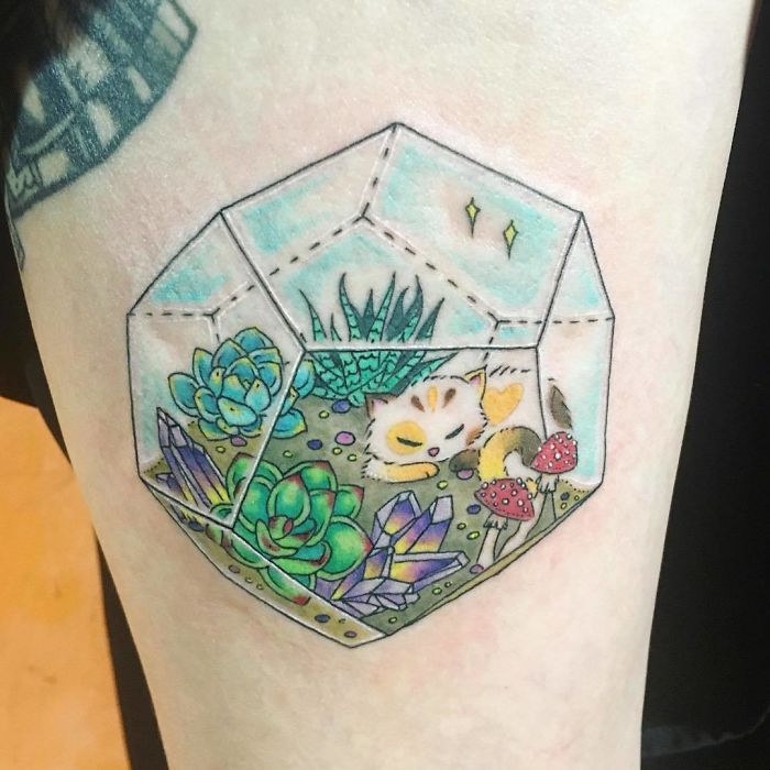 Succulent tattoo with colorful cat and mushrooms in a geometric design on skin.