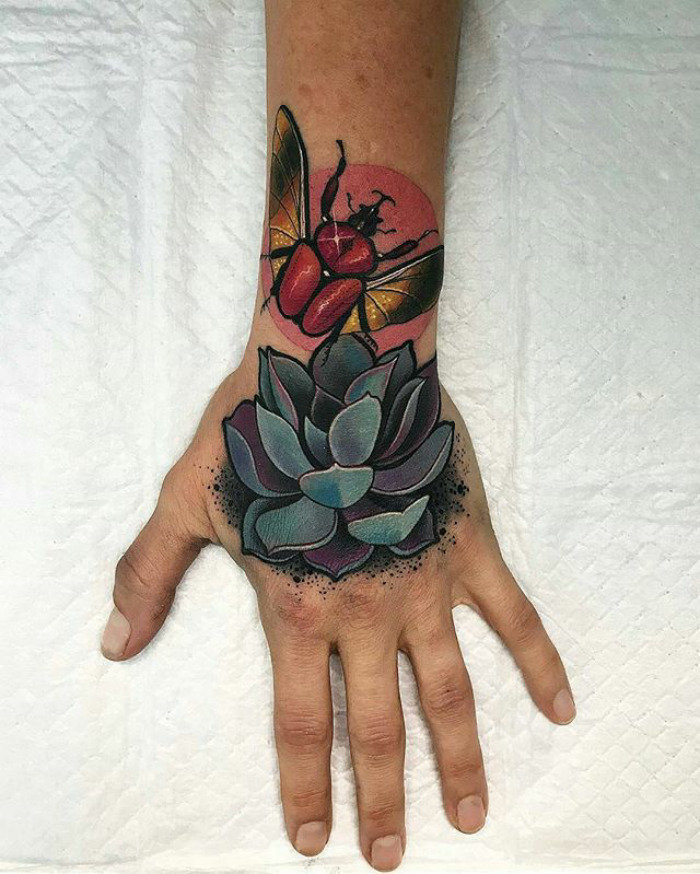 Hand with a colorful succulent tattoo featuring beetle design, emphasizing love for succulent art.