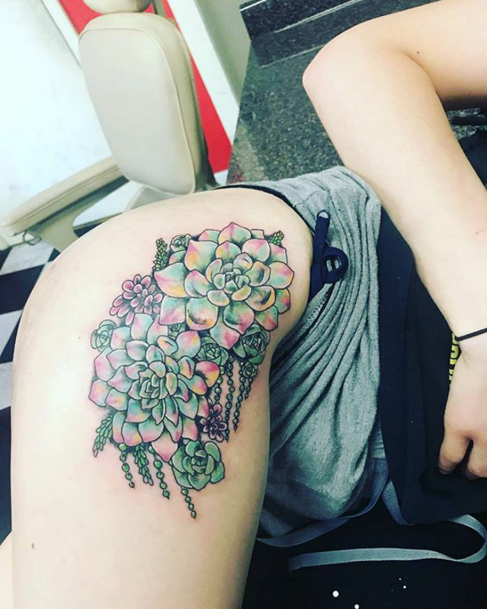 Colorful succulent tattoo on thigh with detailed floral design.