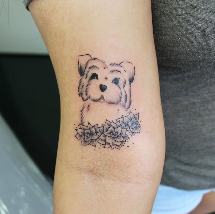 Succulent tattoo featuring a cute dog surrounded by succulent plants on a person's arm.