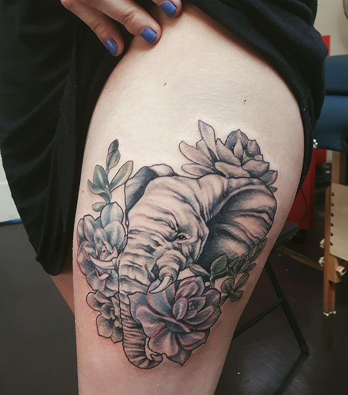 Tattoo of an elephant surrounded by colorful succulents on an upper thigh.