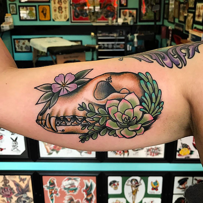 Succulent tattoo featuring a skull with vibrant flowers, beautifully inked on an arm in a tattoo studio.