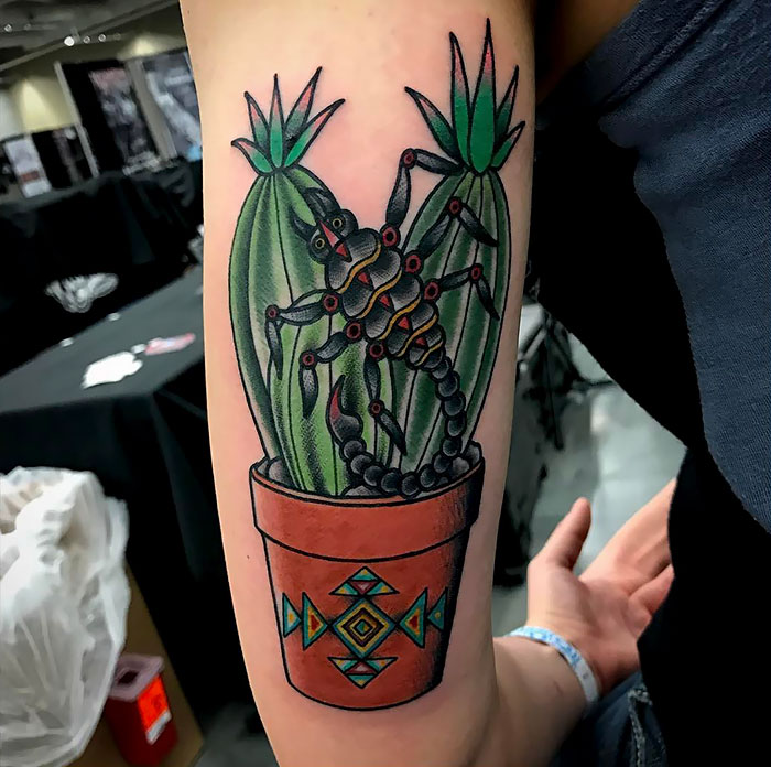 Vibrant succulent tattoo featuring a scorpion design, in a decorative pot, on a person's arm.