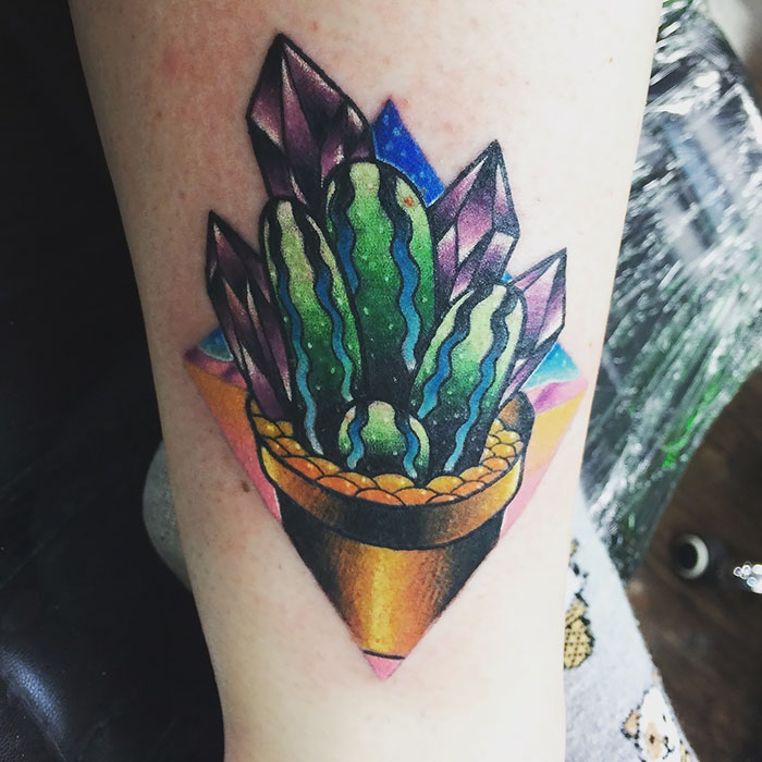 Colorful succulent tattoo featuring geometric shapes and crystals on forearm.
