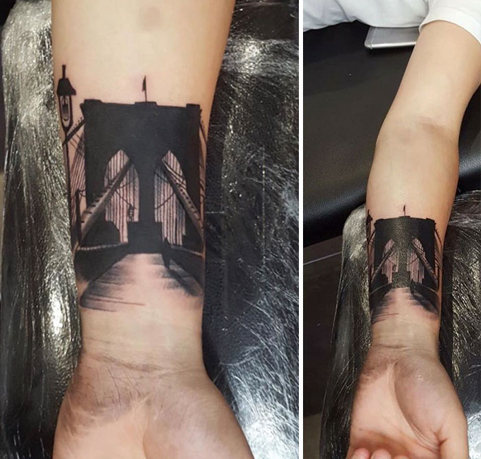 Forearm tattoo depicting architectural design of a bridge, showcasing intricate details and shadows.