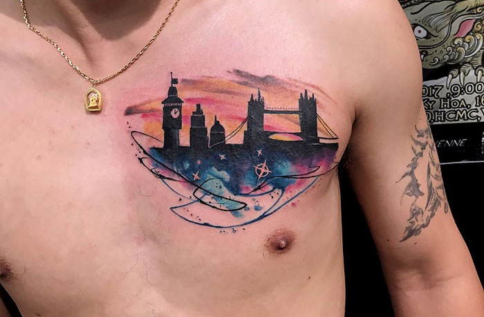 Chest tattoo featuring an architectural skyline with colorful background.
