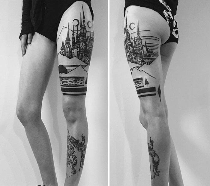 Thigh tattoo featuring intricate architecture designs in black ink on a woman's leg.