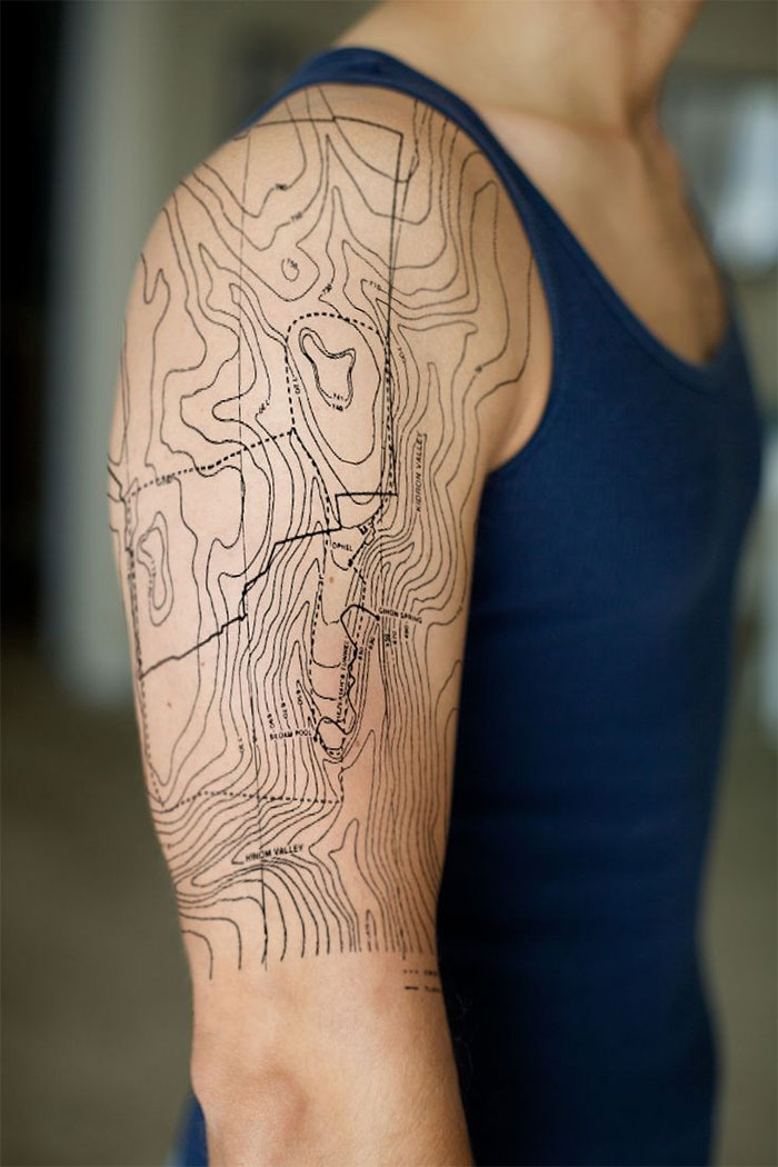 Detailed architecture tattoo on a person's arm, resembling a topographic map, in a minimalistic style.