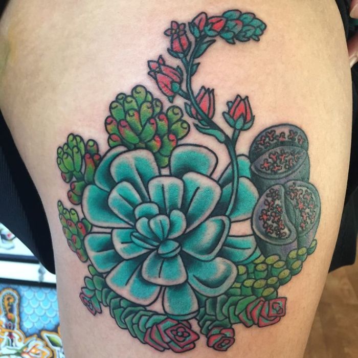 Colorful succulent tattoo design with green and red accents, featuring detailed plant elements on skin.