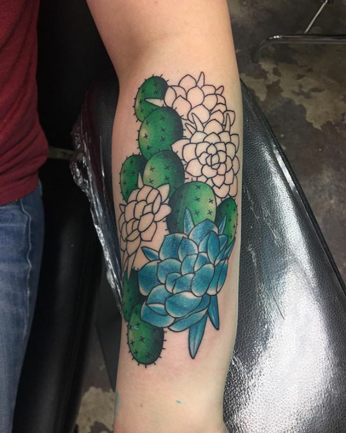 Colorful succulent tattoo design on forearm featuring cacti and flowers.