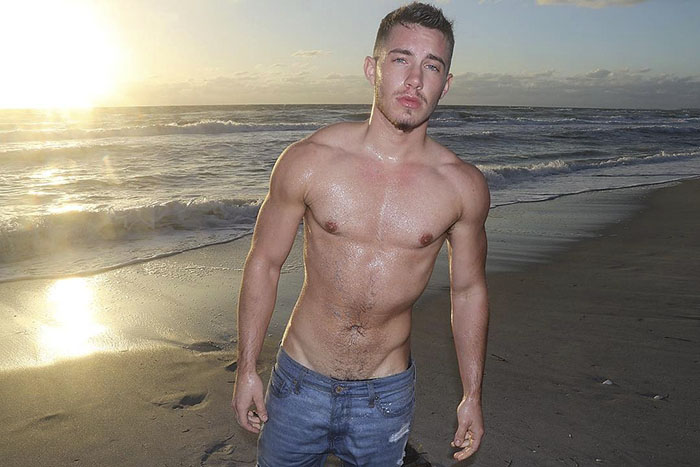Shirtless man standing on the beach during sunset, showcasing a female-to-male transition. Shirtless man standing on the beach during sunset, showcasing a female-to-male transition.