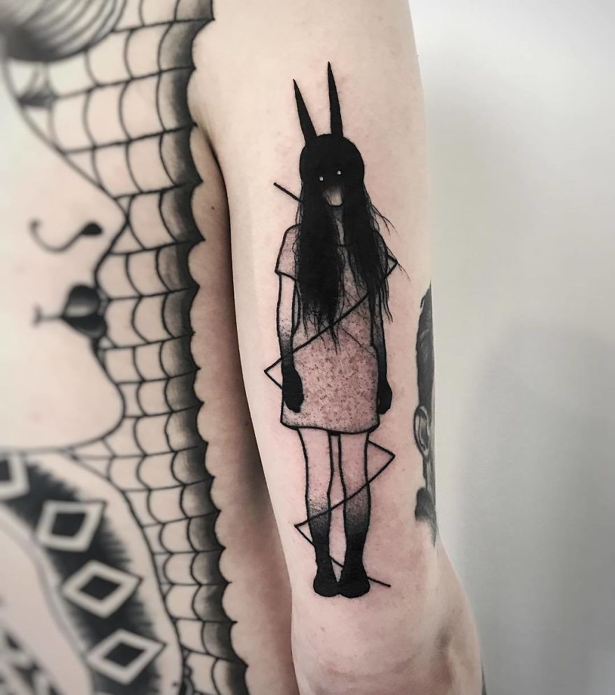 Faceless girl tattoo with bunny ears and dark hair on arm, showcasing slightly erotic style.