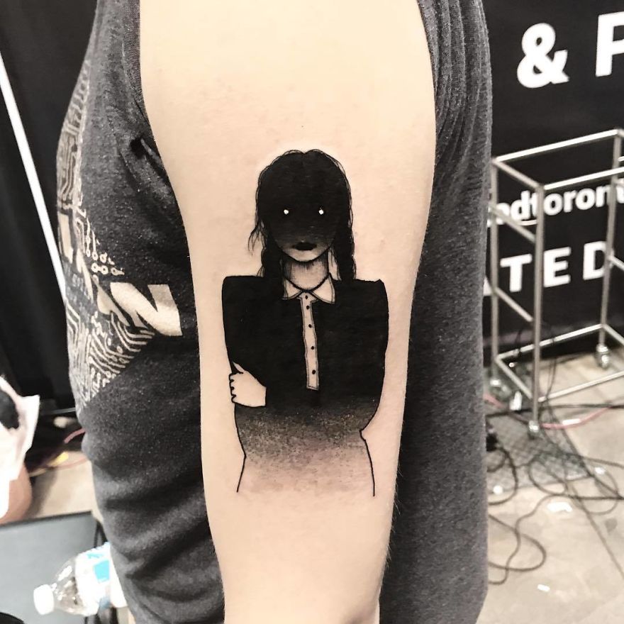Tattoo of a faceless girl on arm, slightly erotic and mysterious, with dark hair and a buttoned shirt.