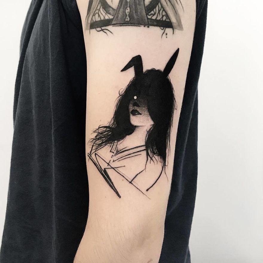 Tattoo of a faceless girl with dark hair and bunny ears on an arm, in a minimalist style.