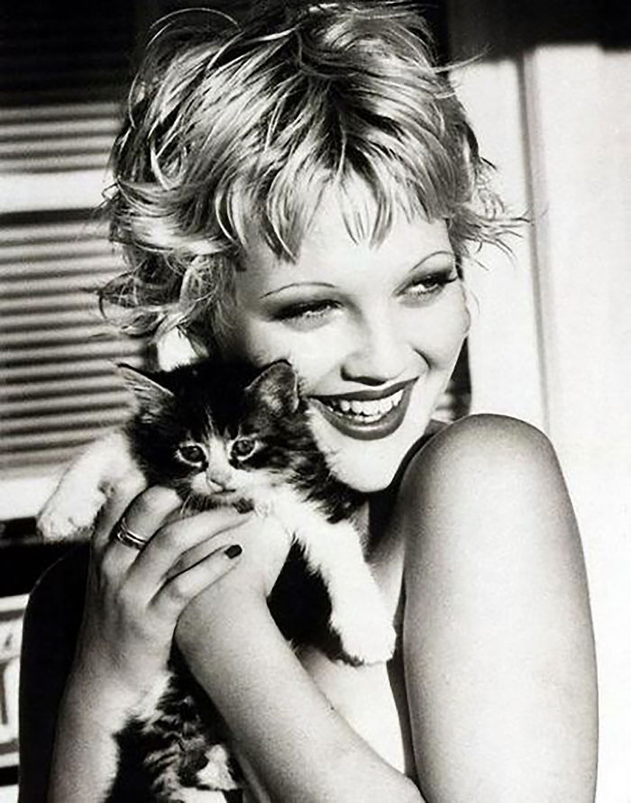 Black and white photo of a famous person smiling while holding a fluffy cat close, highlighting famous people and their cats.