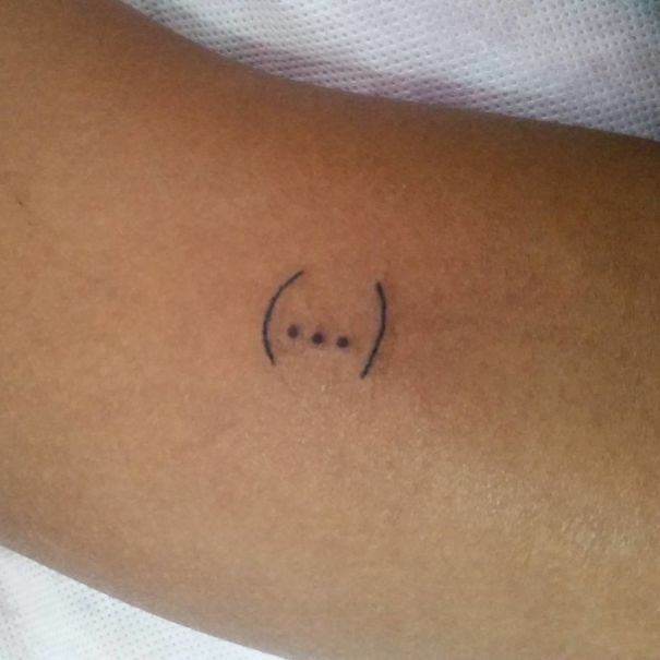 Tattoo of three dots with parentheses on skin by Brazilian artist known for unique drawing style.