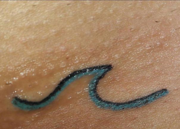 Simple wave tattoo in black and blue by Brazilian tattoo artist on skin.