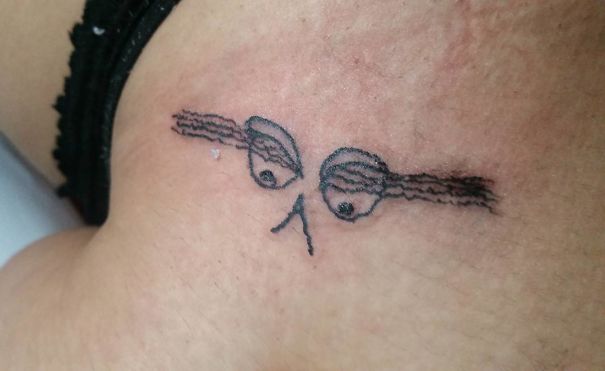 Amateur tattoo by Brazilian artist showing abstract eyes and brows on skin.