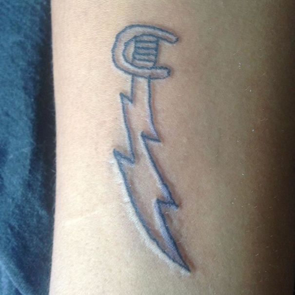 Tattoo of a simple, abstract lightning bolt design by a Brazilian artist on a person's arm.