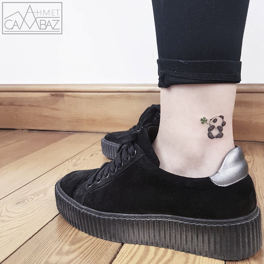 Minimal panda tattoo on ankle by former Turkish cartoonist, with black sneakers on wooden floor.