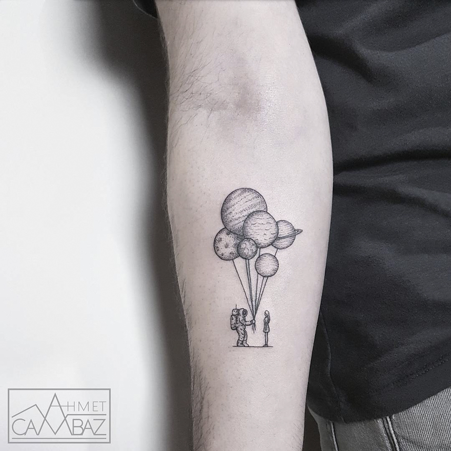 Minimalist tattoo of an astronaut holding planet balloons, on a forearm by a former Turkish cartoonist.