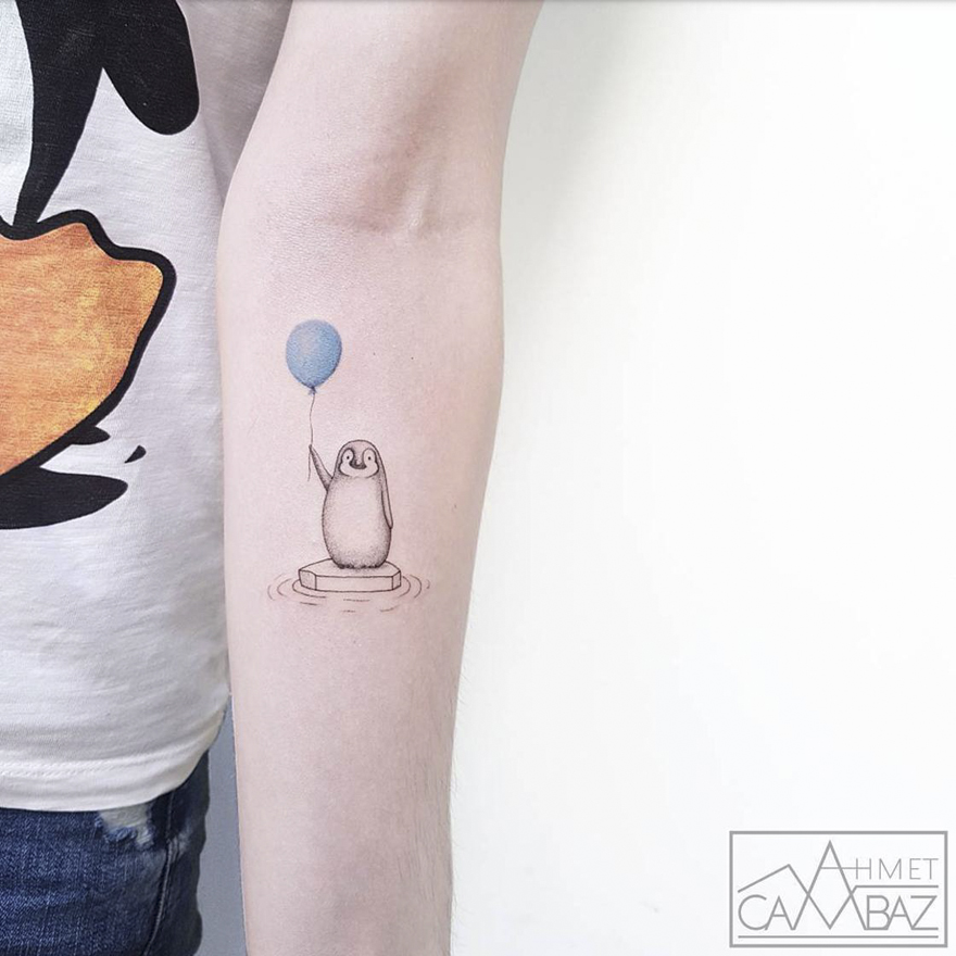 Simple striking tattoo of a cute penguin holding a blue balloon on a person's arm.