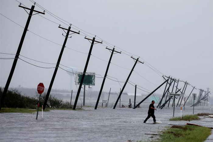 A Man Walks Through Floodwaters And Onto The Main Road After Surveying His Property