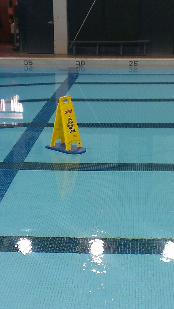 "Caution wet floor" floating in the swimming pool