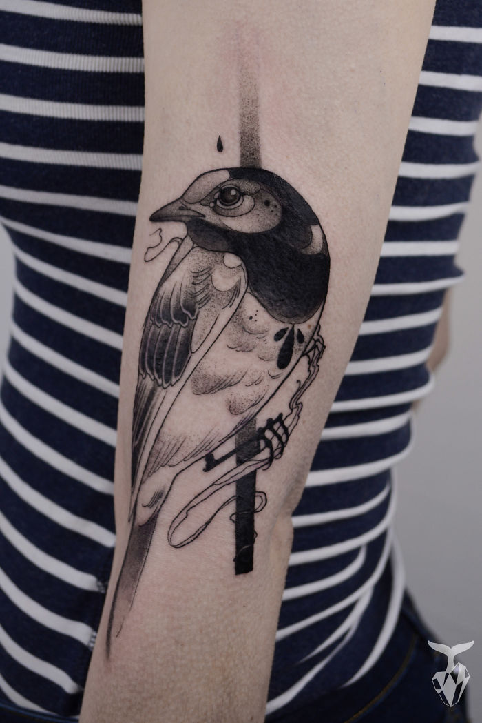 Nature and Art Nouveau inspired tattoo of a bird on a person's arm with striped shirt.