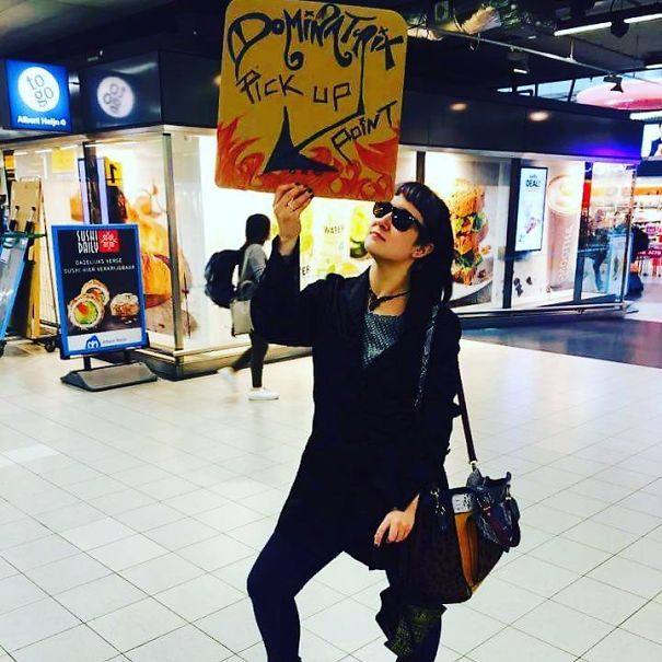 Person holding a funny airport pickup sign at baggage claim, creating a humorous moment in the terminal.