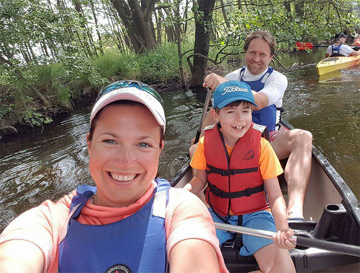 Family kayaking on a river, smiling, showing how depression symptoms have no face.