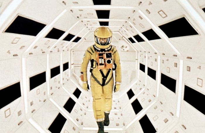 Astronaut in a yellow suit walking through a futuristic white tunnel in a classic scene from 2001: A Space Odyssey movie.