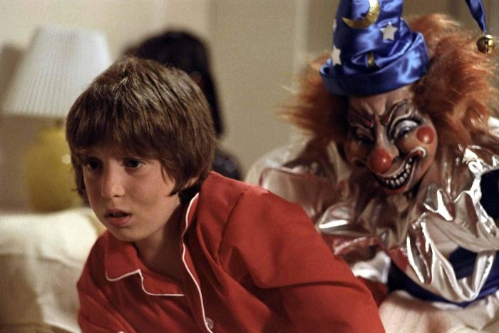 Scene from Poltergeist movie showing a frightened boy in red pajamas with a creepy clown for fun facts about movies.
