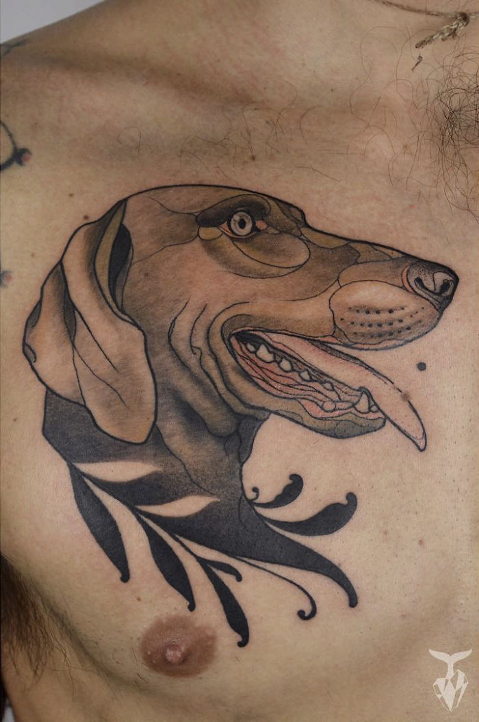 Nature and Art Nouveau inspired tattoo of a stylized dog head on a person's chest.