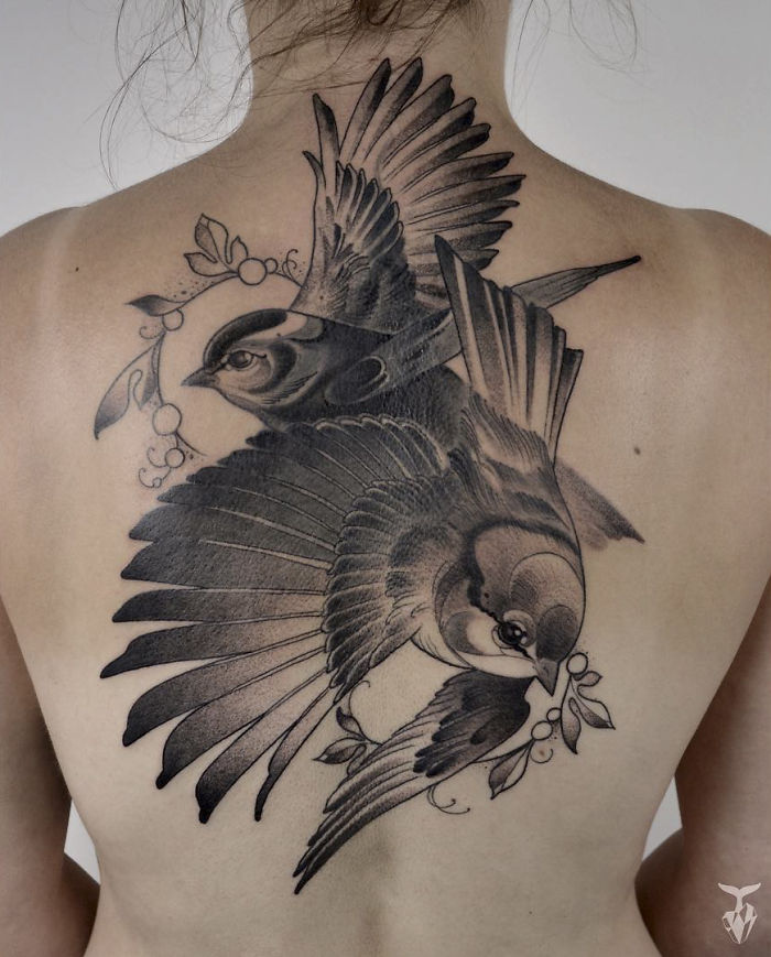 Nature and Art Nouveau inspired tattoo of two detailed birds on a person's back.