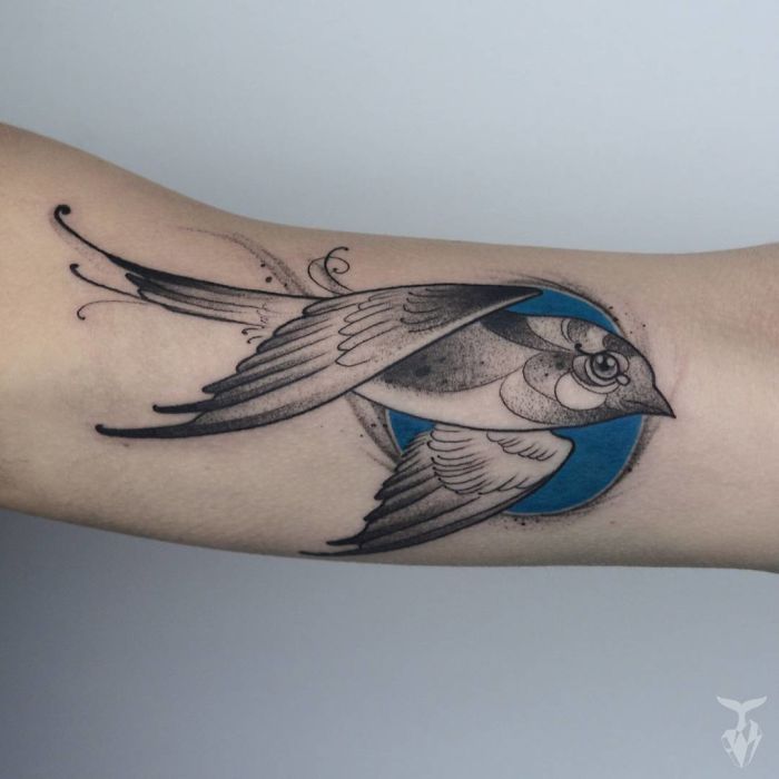 Nature-inspired Art Nouveau tattoo of a bird with a blue background on an arm.